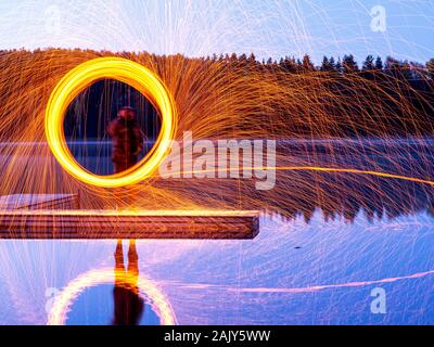 Filage de la laine d'acier de gravure, d'une douche d'étincelles brillantes de la filature de la laine d'acier, de beaux reflets dans l'eau Banque D'Images