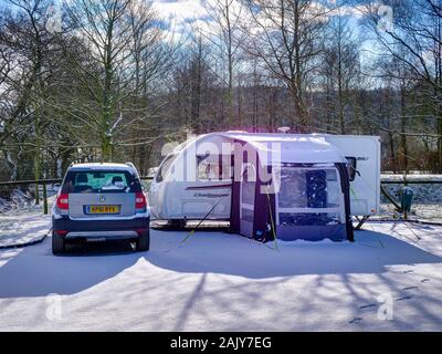 Une femelle caravanier ouvre une fenêtre dans un Challenger 514 Swift Sport caravane, garée à côté d'un Skoda Yeti voiture remorquage sur une journée d'hiver ensoleillée après une baisse de Banque D'Images