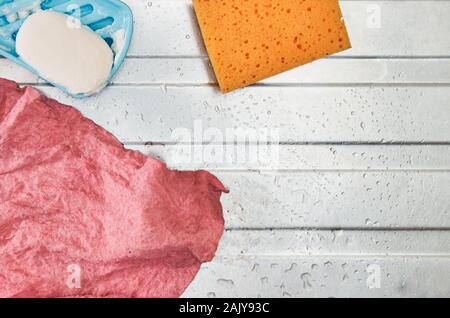 Sale torchon humide rose utilisé (gant), visqueux et d'un savon éponge cuisine orange. Placé sur le dessus d'un évier de cuisine en acier avec des gouttelettes d'eau Banque D'Images