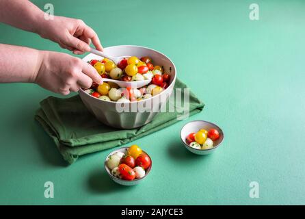 Servir la salade d'été. Salade Caprese de melon dans un bol sur la table verte. Femme de tomates cerises avec salade de melon et mozzarella Mini. Alimentation saine. Banque D'Images