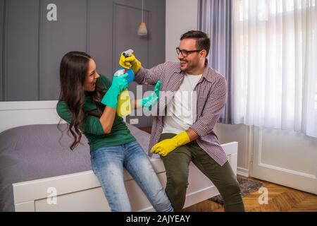 Jeune couple s'amuse lors du nettoyage de leur appartement. Banque D'Images