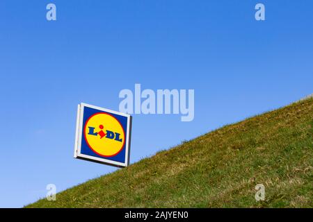 Un Lidl supermarché signer pokes out au-dessus d'une colline d'herbe verte Banque D'Images