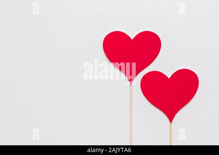 Stock photo de deux coeurs en papier rouge sur un fond blanc. Les coeurs ont un bâton en bois Banque D'Images