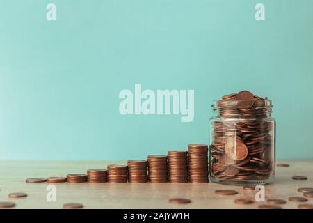 Stock photo d'un escalier ascendant de pièces sur un fond bleu avec un pot plein de pièces Banque D'Images