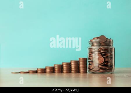 Stock photo d'un escalier ascendant de pièces sur un fond bleu avec un pot plein de pièces Banque D'Images