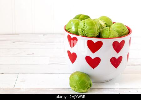 Choux de bruxelles vert frais dans un plat couvert dans les coeurs. Banque D'Images