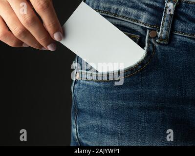 Part d'une jeune fille met une carte d'affaires dans une poche de jeans Banque D'Images