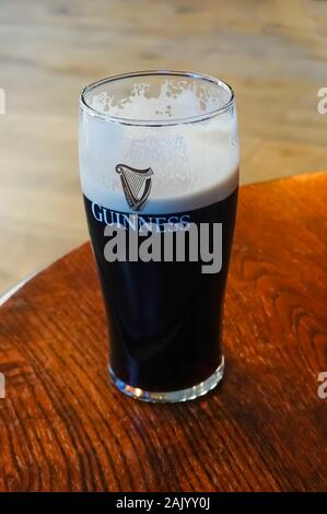 Une pinte de Guinness piquant dans un grand verre de tulipe mince Banque D'Images