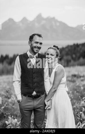 noir et blanc de la mariée et du marié souriants heureux devant les montagnes Banque D'Images