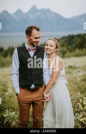 La mariée et le marié nouvellement mariés se tiennent dans le champ des fleurs Banque D'Images