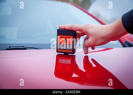 La mesure de l'épaisseur de la couche de peinture de voiture couleur rouge à l'aide d'une jauge d'épaisseur de peinture. Banque D'Images