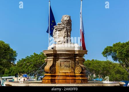 Une fontaine baroque avec un grand lion de calcaire qui garde sa patte sur dado avec l'image taillée. Banque D'Images