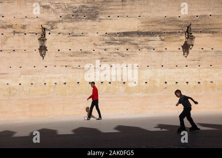 Un piéton et un garçon sur les rollers dans le paysage de l'après-midi des murs de la cité dans la région de Bab Mechouar et Bab Dekkakin à Fes (fez), Maroc Banque D'Images