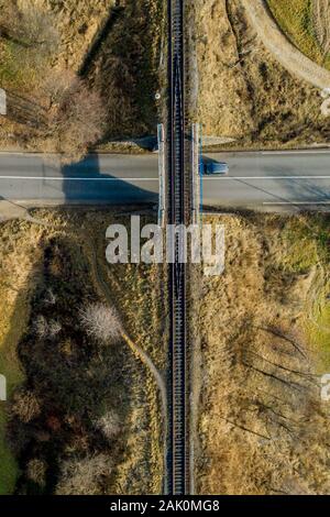 Pont de chemin de fer entre les prairies vertes sur la route à la campagne, vue aérienne Banque D'Images
