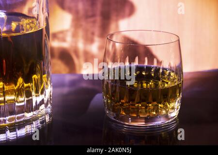 Carafe et verre avec un fond de whisky sur Fiery. Carafe et verre sont mis en miroir sur une table en verre. Banque D'Images