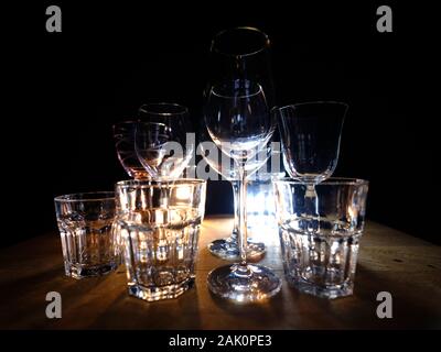 Gros plans de- vin, spiritueux et long drink--verres sur une étagère en bois dans un bar, en face d'un fond sombre, illuminé par spo colorés Banque D'Images