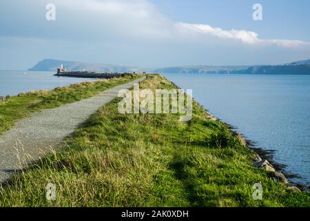 À Fishguard, Pays de Galles, vous pouvez suivre un sentier de randonnée sur la jetée vers le phare au loin. Banque D'Images