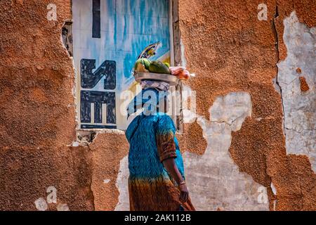 Saloum, Sénégal, 26 avril 2019 : Le Sénégal non identifiée femme transportant une pastèque et autres fruits sur sa tête dans la ville de Saloum et portant la Banque D'Images