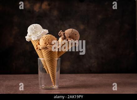 Trois sortes de glaces dans des cônes sur fond sombre Banque D'Images