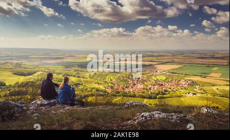 Deux personnes (couple) sur une montagne et à la recherche dans la vallée le beau paysage d'automne avec village, vignes et champs. Ciel bleu, nuages blancs Banque D'Images