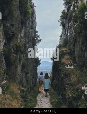 Deux jeunes femmes marchant sur un chemin entre les montagnes nuageux par jour Banque D'Images