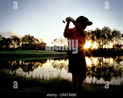 Femme mûre swing club de golf tout en jouant au golf. Banque D'Images