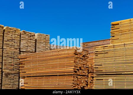 Palettes de pin traité bandes sont vues stockées dans un constructeur de machines de triage. Des poutres et des planches sous un ciel bleu avec copie espace. Banque D'Images