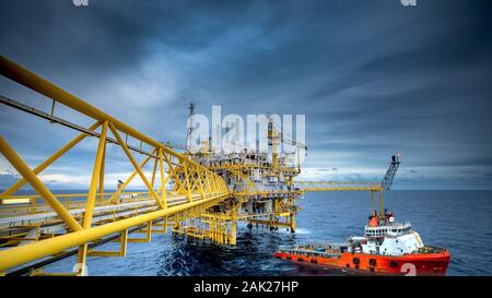 La boîte d'expédition est chargé à partir d'une plate-forme pétrolière offshore pour le navire de ravitaillement au coucher du soleil. Banque D'Images