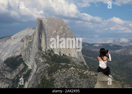 Femme voyageur solitaire prenant un selfie audacieux avec vue Sur Half Dome - Glacier point, Yosemite Banque D'Images