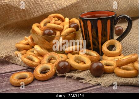 Bagels, petits chocolats, une tasse de thé et un tissu de fabrication locale sur un fond de bois close-up Banque D'Images