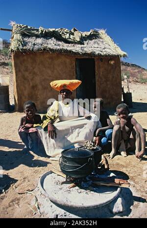 Une Femme Herero avec leurs enfants en face d'une source de chaleur avec une marmite, la Namibie. (Photo non datée) | conditions dans le monde entier Banque D'Images