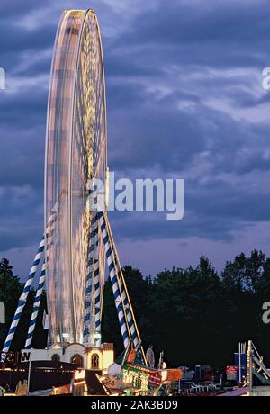 Un ligthed grande roue tournant sur le Festival folklorique de Nuremberg à Nuremberg dans la nuit. Le festival a lieu chaque année sur l'ancien parti Nazi rally gr Banque D'Images