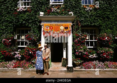 Un couple dans la petite ville de Rye en face de la Maison du Vin Blanc couvert de lierre et de fleurs. (Photo non datée) | conditions dans le monde entier Banque D'Images