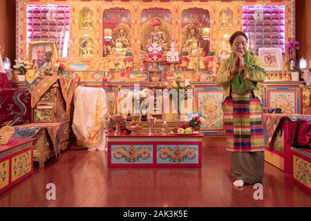 Une femme bouddhiste dévot en priant et en méditant sur l'autel dans un temple dans le Queens, New York. Banque D'Images