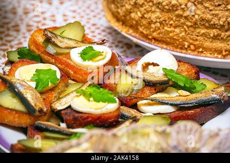 Des sandwichs avec sprats fumé, oeuf dur, les cornichons et le persil dans une assiette. Selective focus Banque D'Images