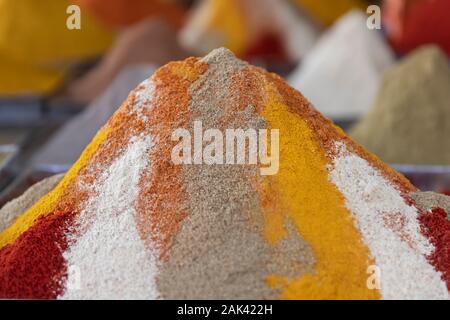 La poudre de chili, le poivre de cayenne, paprika, cardamome, cumin. Heap colorés de différentes épices dans l'hebdomadaire marché rural de Rissani, Maroc. Banque D'Images