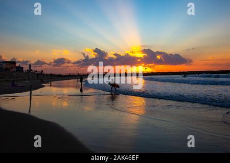 Silhouette de surfers sur la plage de la mer Méditerranée. Photographié à Tel Aviv au coucher du soleil Banque D'Images