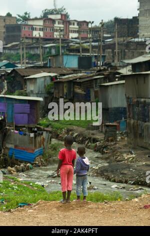 Deux jeunes enfants kenyans se tenir à l'égard de la rivière et dans les bidonvilles de Mathare, à Nairobi, Kenya Banque D'Images