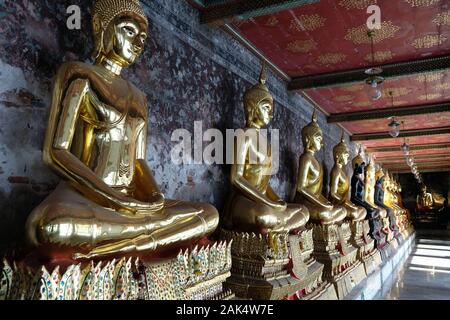 Thaïlande Bangkok Wat Suthat Thepwararam - Temple d'or des statues de Bouddhas méditant assis dans une rangée dans un couloir Banque D'Images