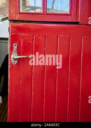 Rouge antique porte en bois avec une poignée de porte métallique. Banque D'Images