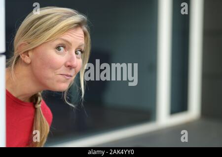 Drôles de adultes mignon femme blonde, à l'angle et à la recherche à l'appareil photo avec visage amical. Close-up portrait with copy space Banque D'Images