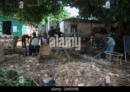 Des chaises en osier tressée pour hommes sur un site de production à côté d'un simple magasin de meubles de plein air à Conakry, Guinée, Afrique de l'Ouest Banque D'Images