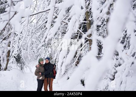 Jeune couple hugging tandis que dehors la randonnée dans une forêt d'hiver Banque D'Images