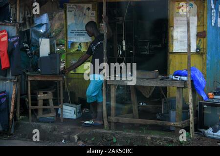 Vue d'un homme devant un petit magasin d'électronique très simple à Conakry, Guinée, Afrique de l'Ouest, attendant ses clients Banque D'Images