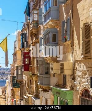 Les rues étroites typiques colorés traditionnels maltais avec fenêtres et volets en bois et d'un balcon, de ciel bleu clair un jour d'été, La Valette, Malte Banque D'Images