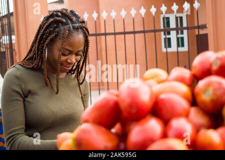 Belle jeune femme africaine vente de tomates dans un marché africain Banque D'Images