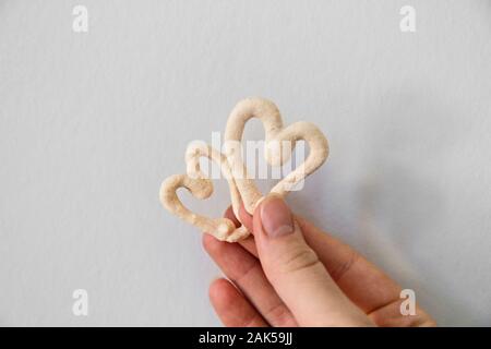 La meringue en forme de coeur deux cookies dans la main Banque D'Images
