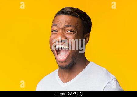 No Man Afro émotionnelle crier fort debout sur fond jaune. Studio Shot Banque D'Images