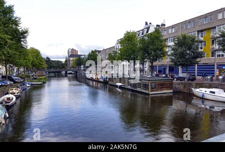 Amsterdam,Hollande,Août 2019. Dans le centre historique une vue qui est un symbole de la ville : une péniche brun amarré au bord du canal. Derrière je Banque D'Images