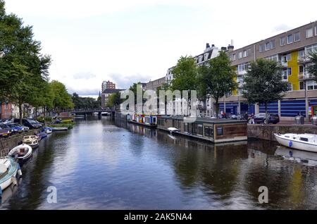 Amsterdam,Hollande,Août 2019. Dans le centre historique une vue qui est un symbole de la ville : une péniche brun amarré au bord du canal. Derrière je Banque D'Images